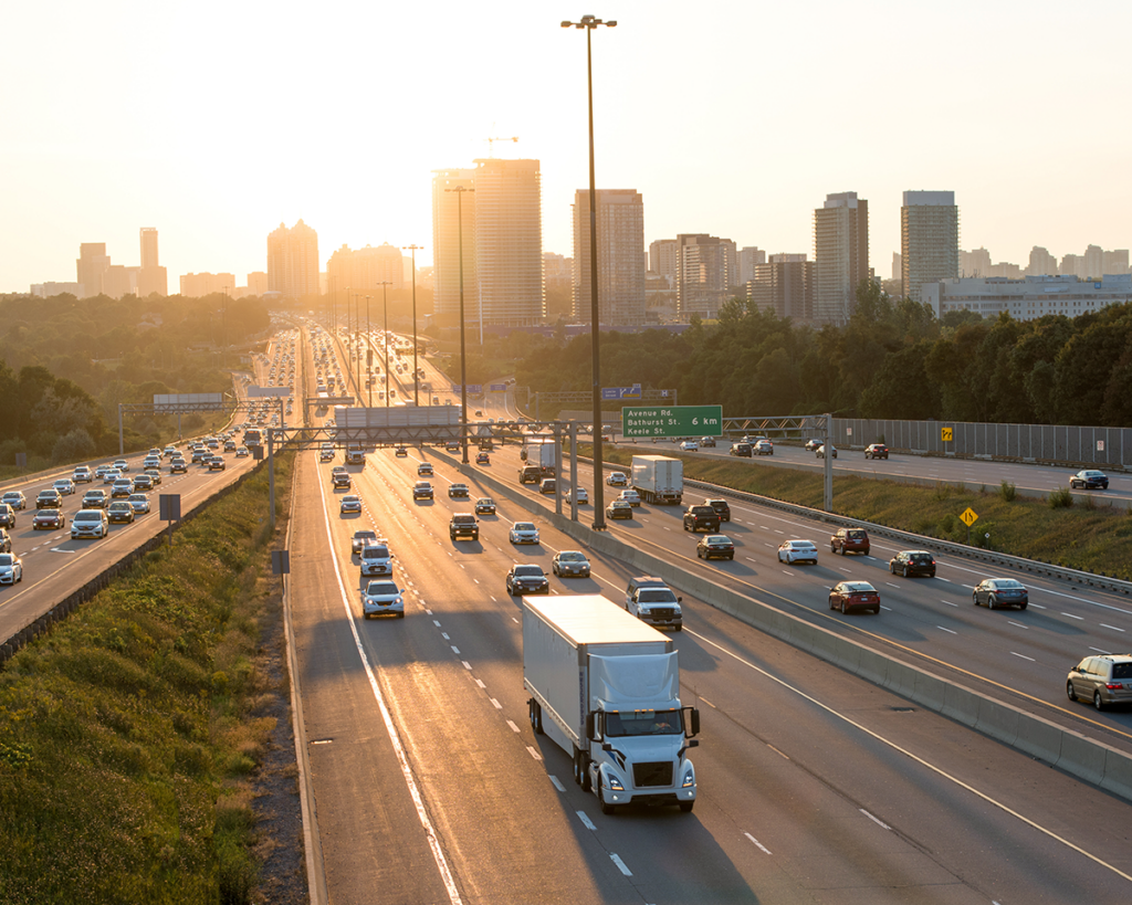 Rodovia movimentada com tráfego intenso ao entardecer, representando logística internacional