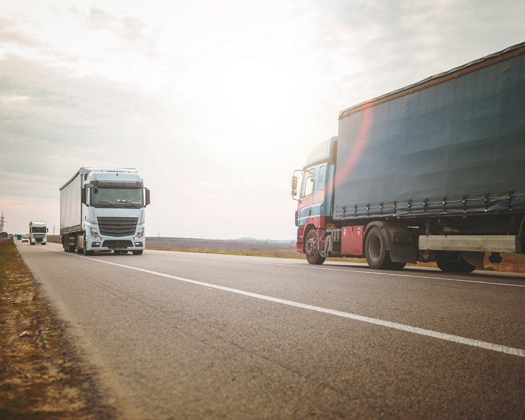 Caminhão rodando em paisagem rural, simbolizando transporte de cargas pela Multilog